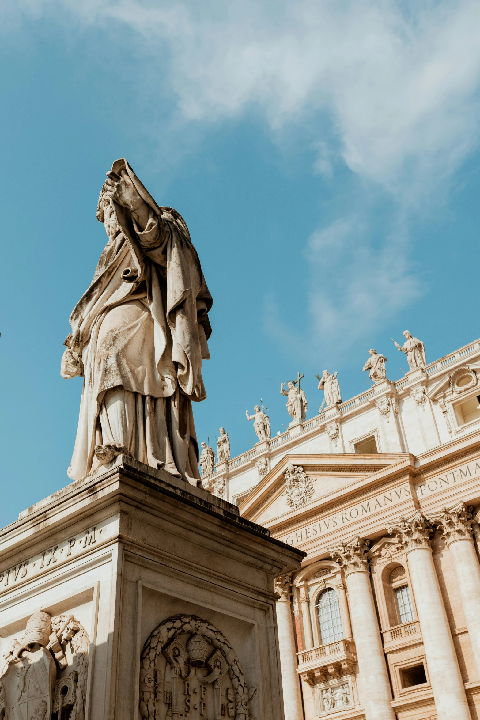 a statue in front of a large building with clouds in the sky