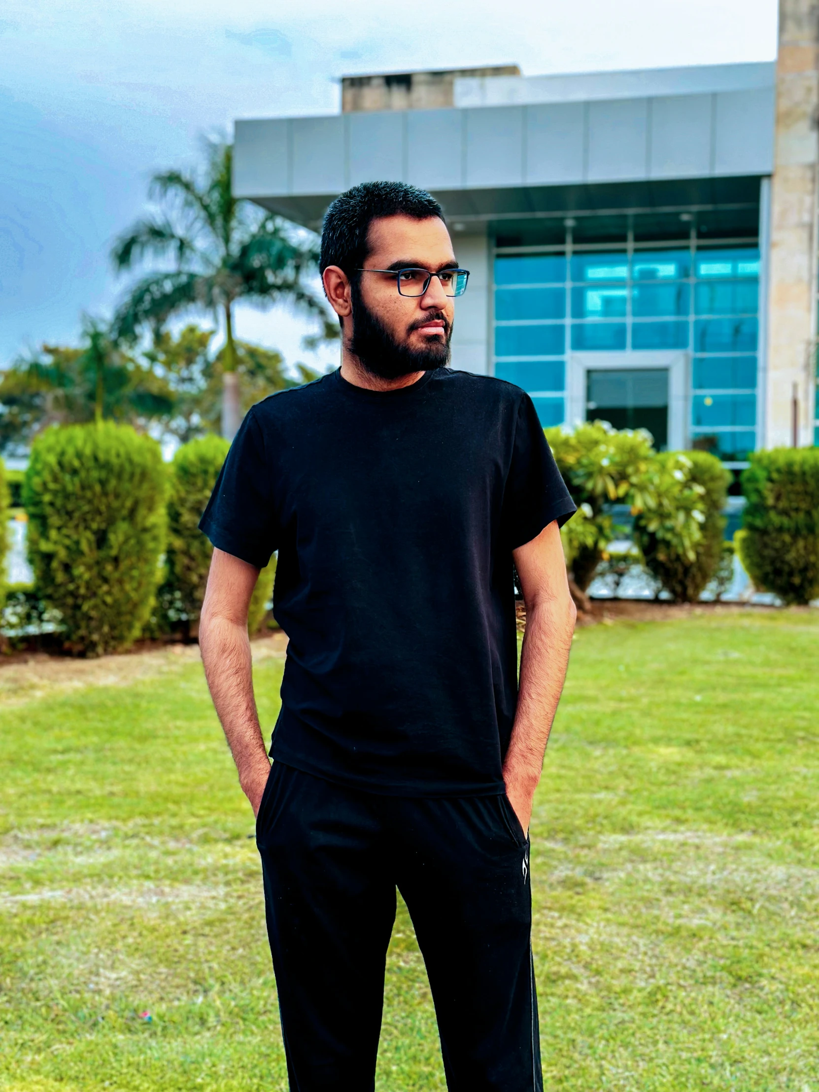 a man in black wearing glasses is standing outside