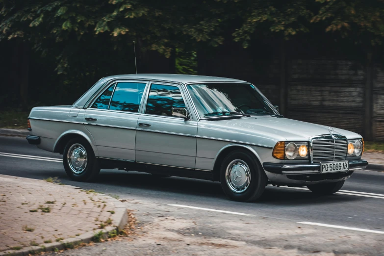 a gray old fashioned car driving down the road