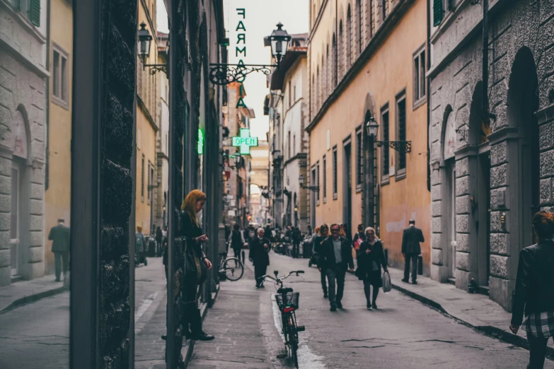 many people are walking down the street and some have bicycles