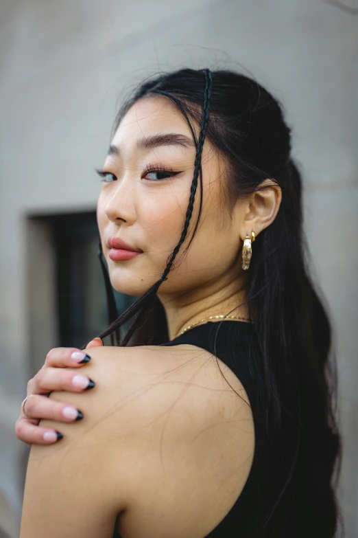 an asian woman wearing gold earrings and black dress