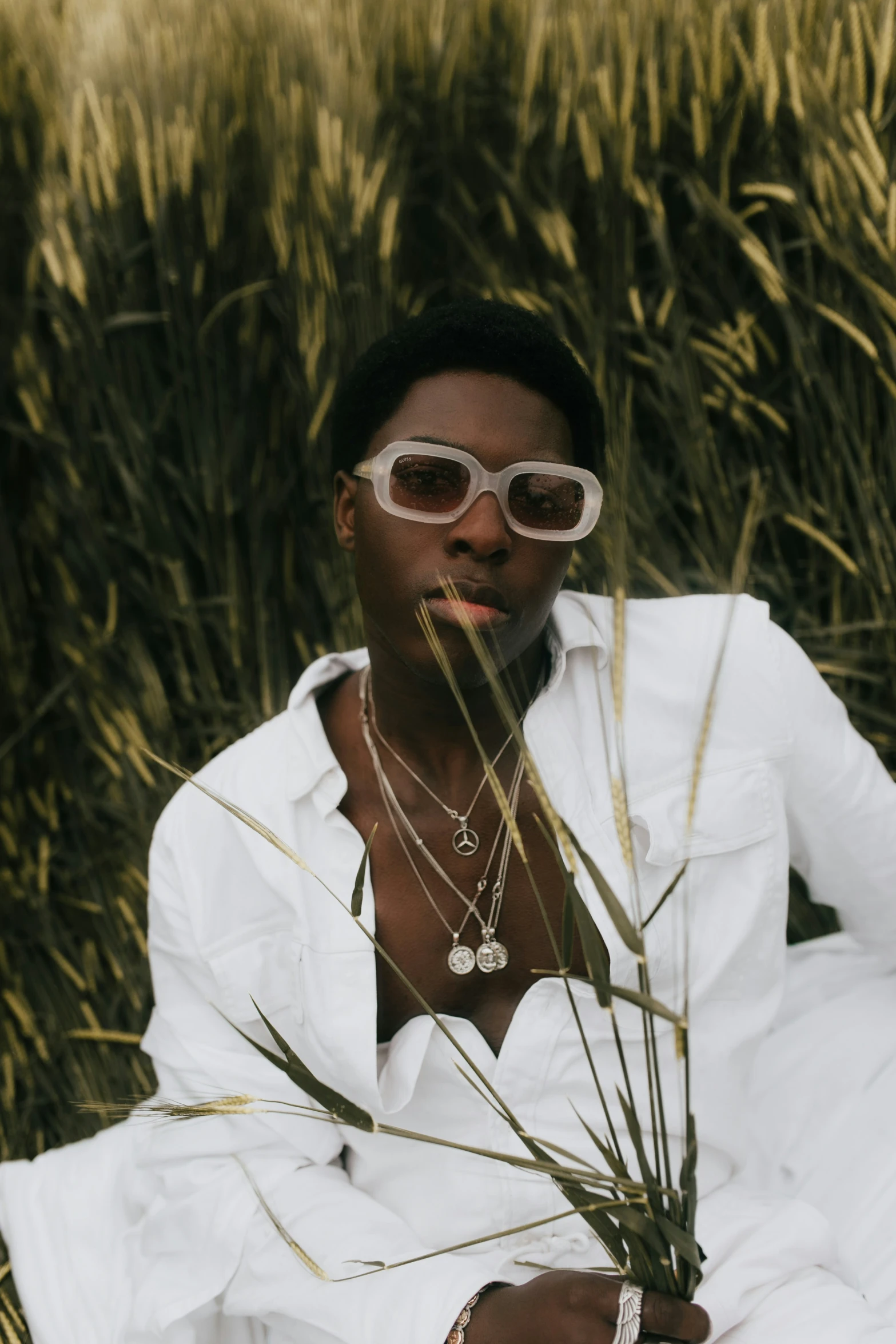 a woman in sunglasses holds grass in her hands