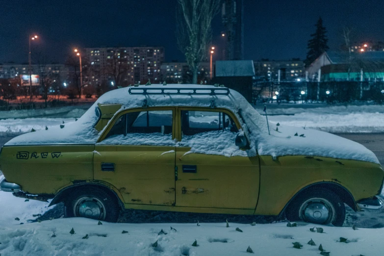 an old car covered in snow in front of a city street