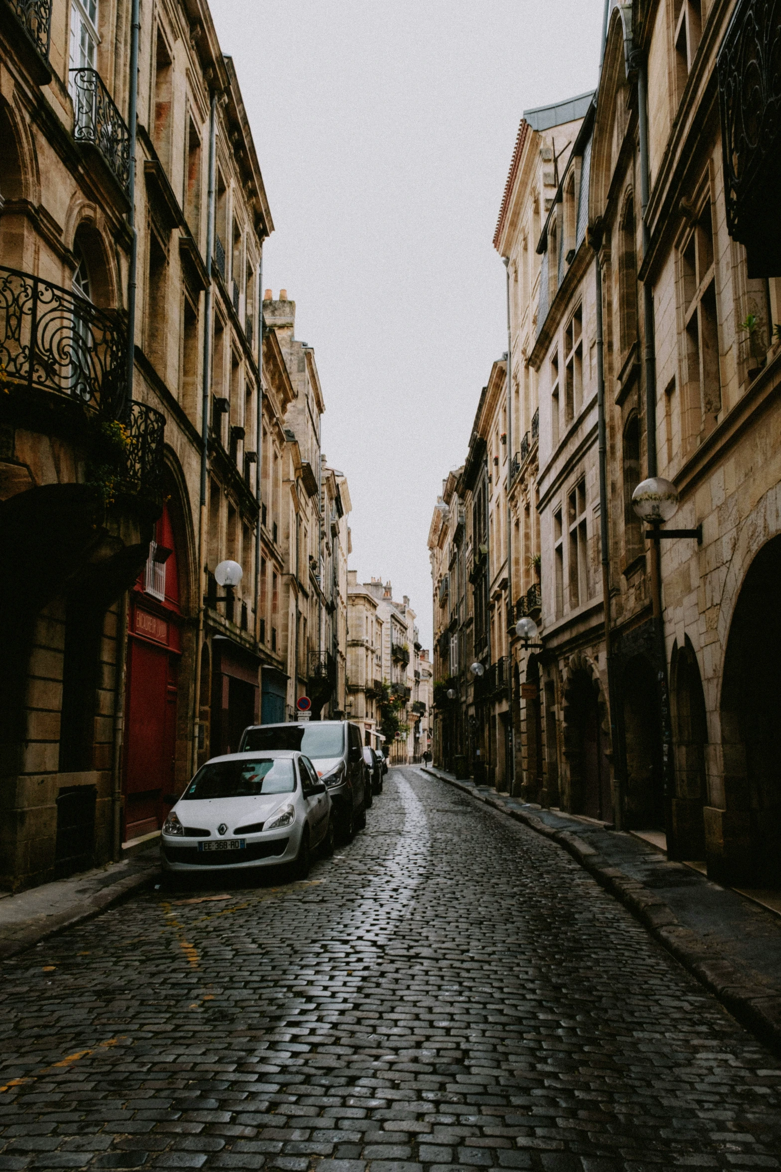 a car on a cobble stone road surrounded by old buildings