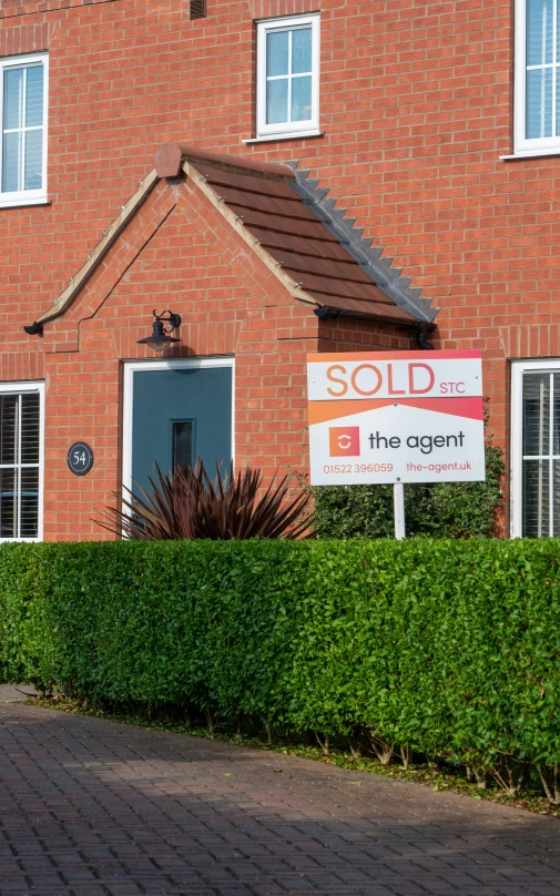 an orange brick house with a sold sign on the front lawn