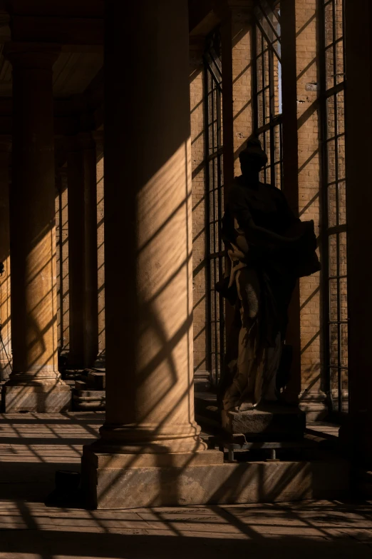 a sunlit hallway with some statues in the dark