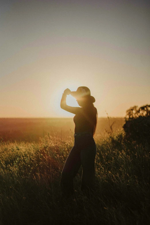 a woman standing in the field taking a po