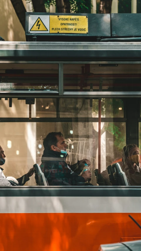 people sitting in a bus and one man is on a cell phone