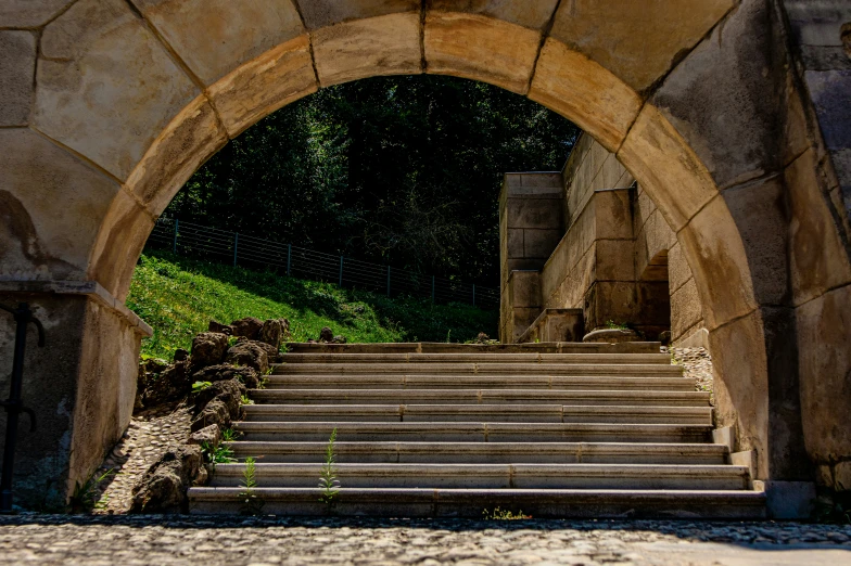 stone stairs leading up to an arch that connects into a field