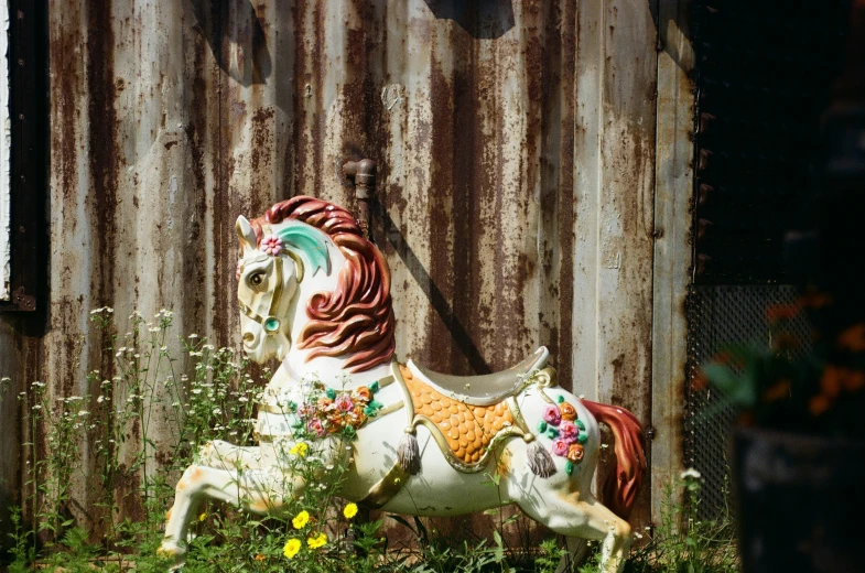 there is a decorative horse on the grass in front of a fence