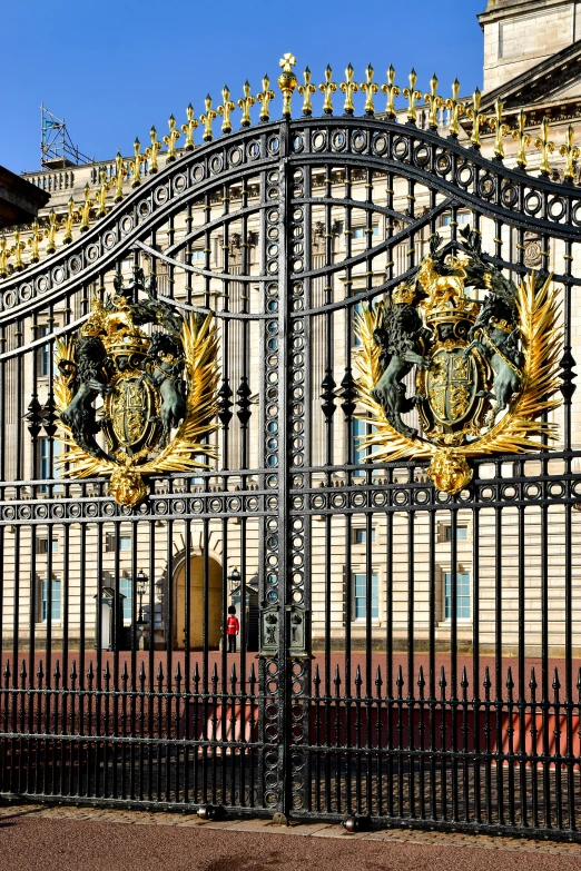 a black and gold fence has two lions at the center