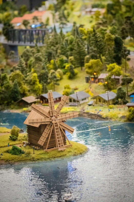 a doll's house with an elaborate windmill near water