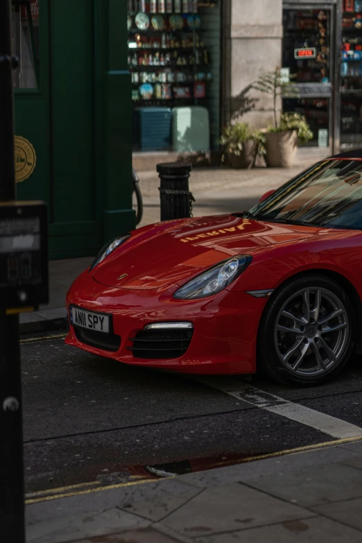 a red porsche roadster is parked on the curb