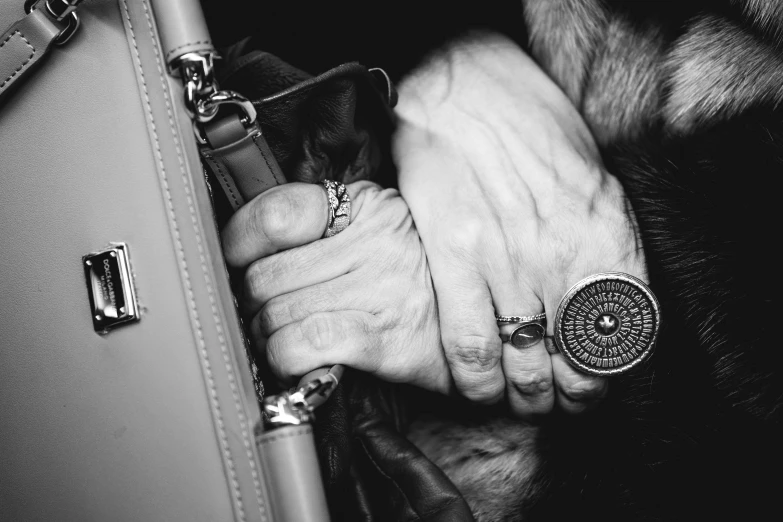 a woman's hands and two rings on her purse