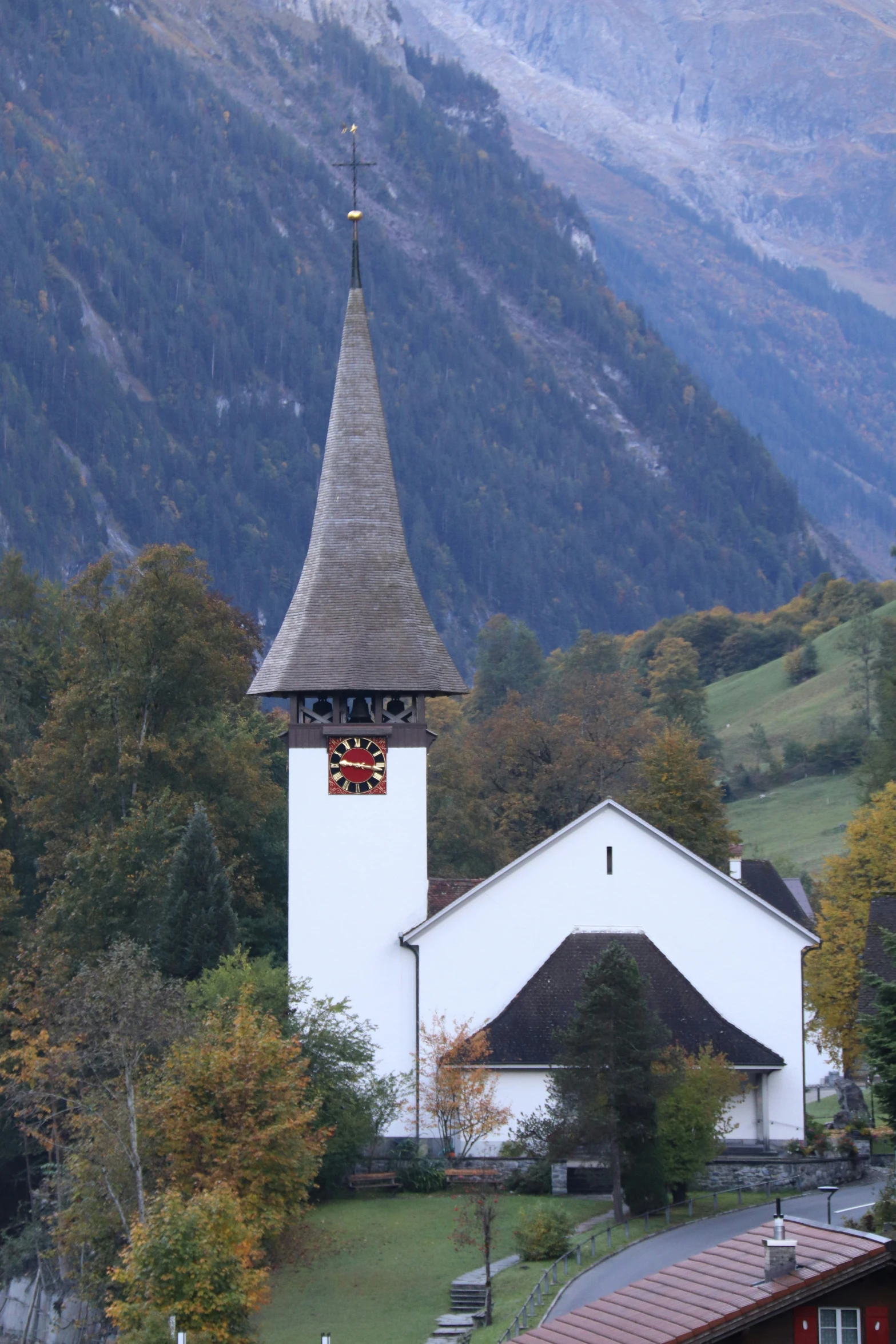 a church with a clock tower and steeple on a hill