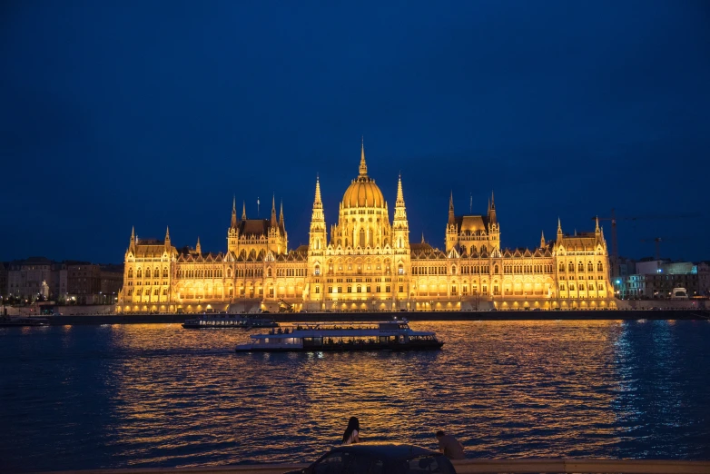 the castle is glowing yellow next to a body of water