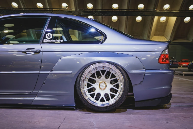 a blue car with some big rims parked near a building