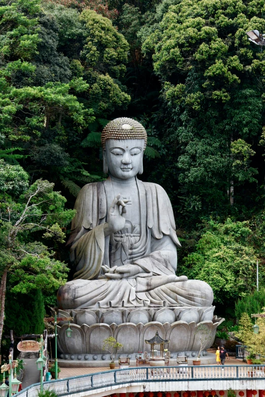 a large white buddha statue sitting inside of a lush green forest