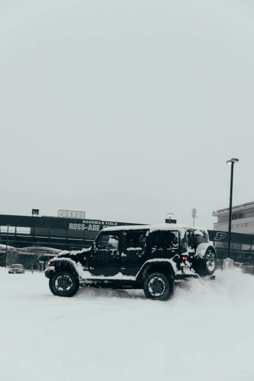 a black jeep is parked next to a building in the snow