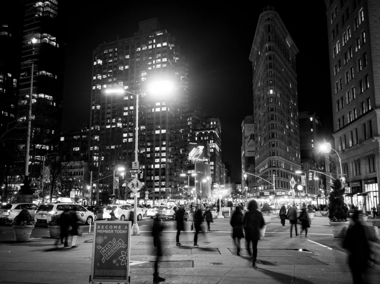 many people walk along the sidewalk in the dark