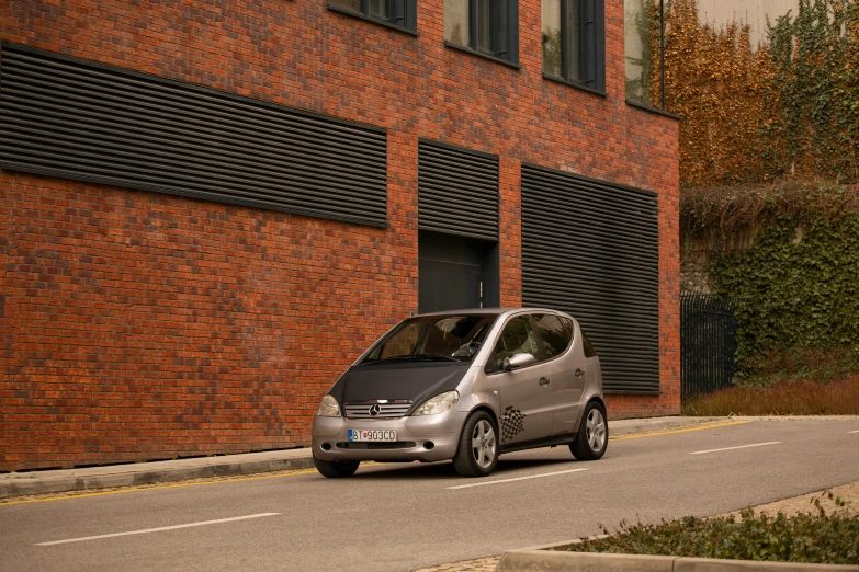 a small gray compact car driving down the road