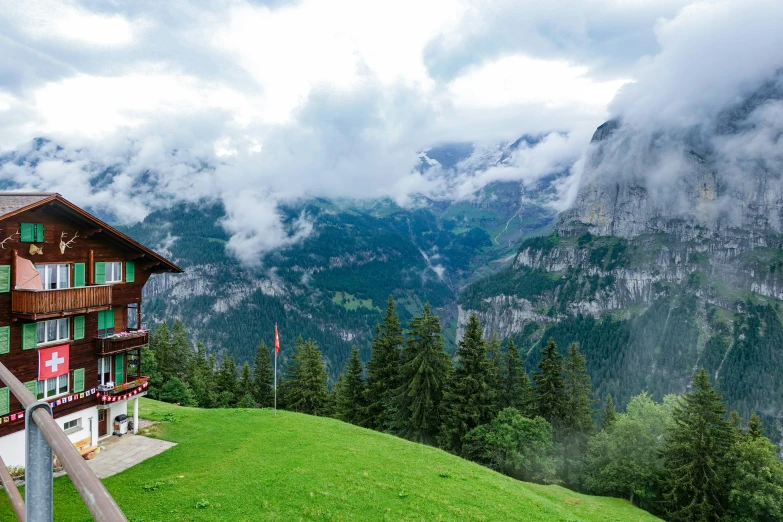 the house sits on a mountain side overlooking green mountains