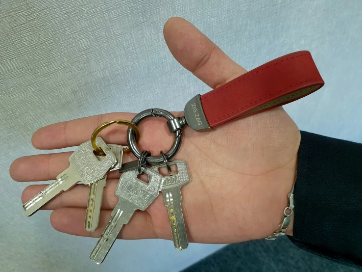 a man's hand holding keys that have been placed in different types of key chains