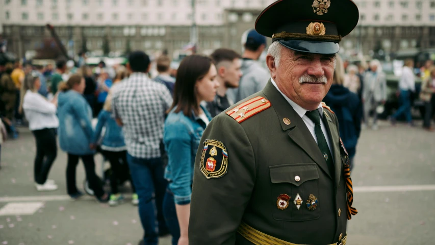 an older man in military uniform and surrounded by a large group of people