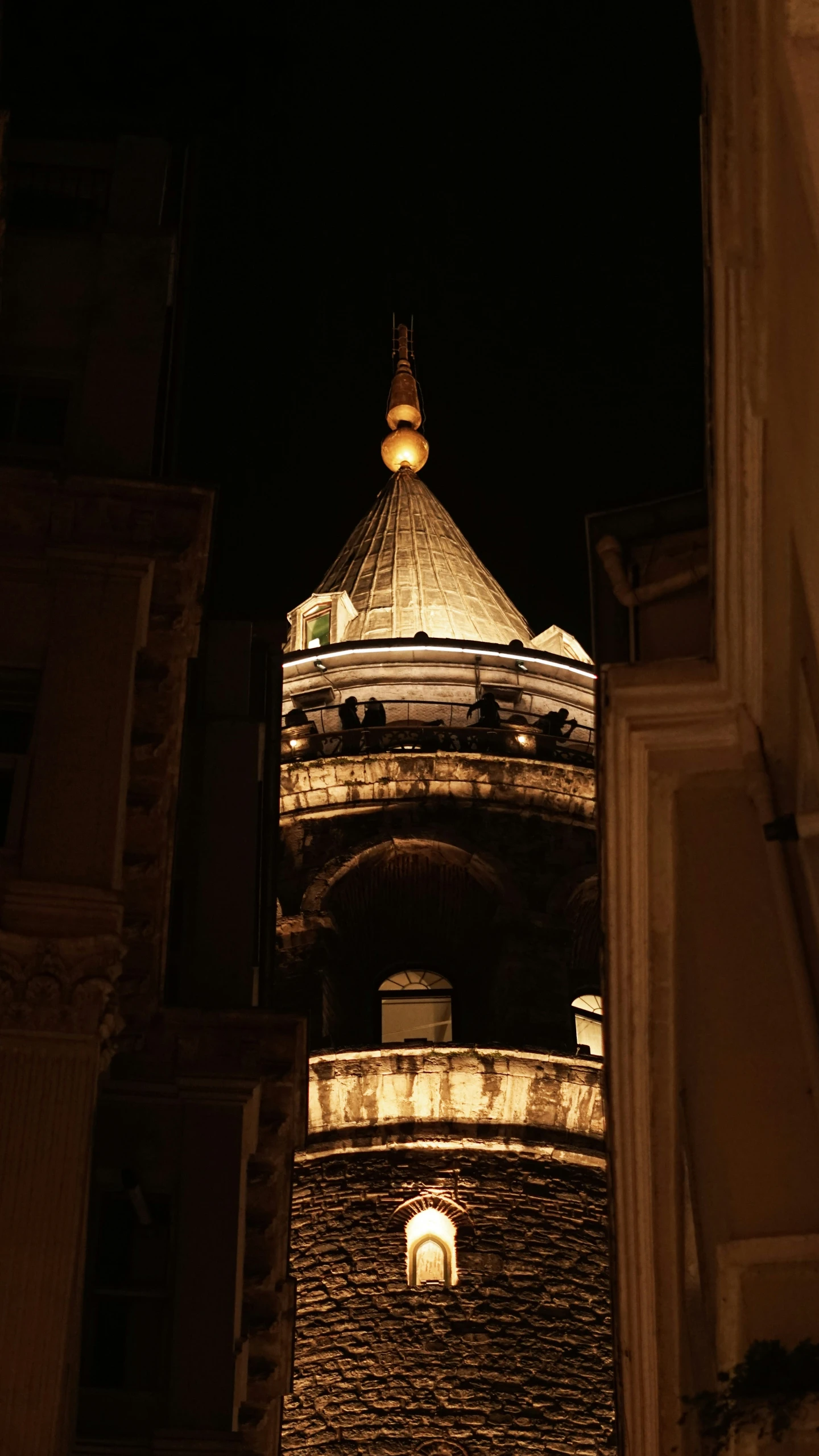 lights shine on a stone building with a clock