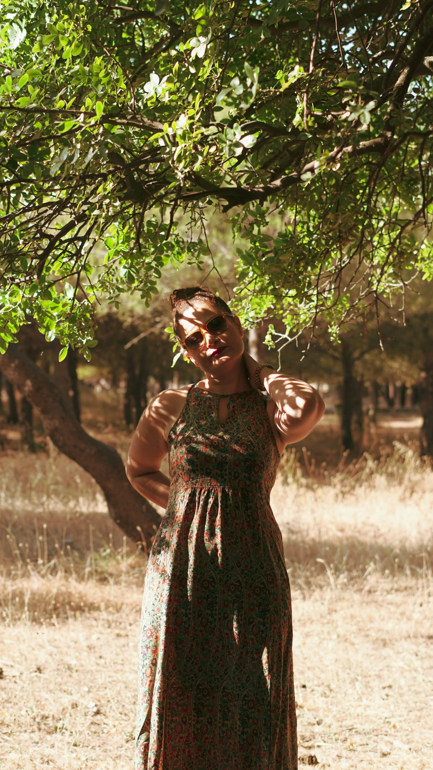 a woman standing under a tree wearing glasses