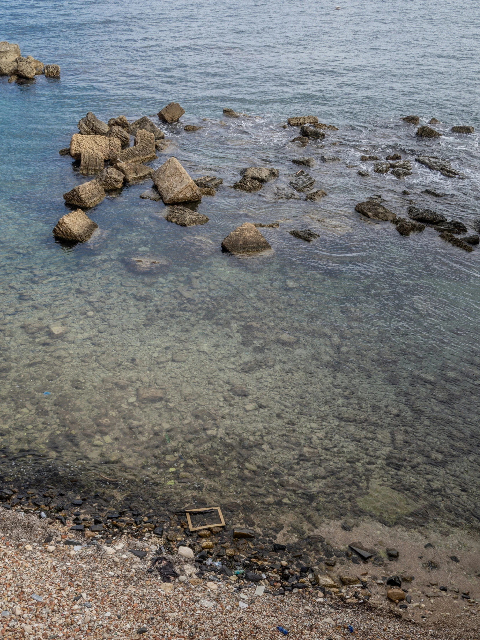 a bench is sitting in the water on a rocky shore