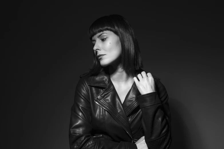 a woman wearing a black leather jacket poses for the camera