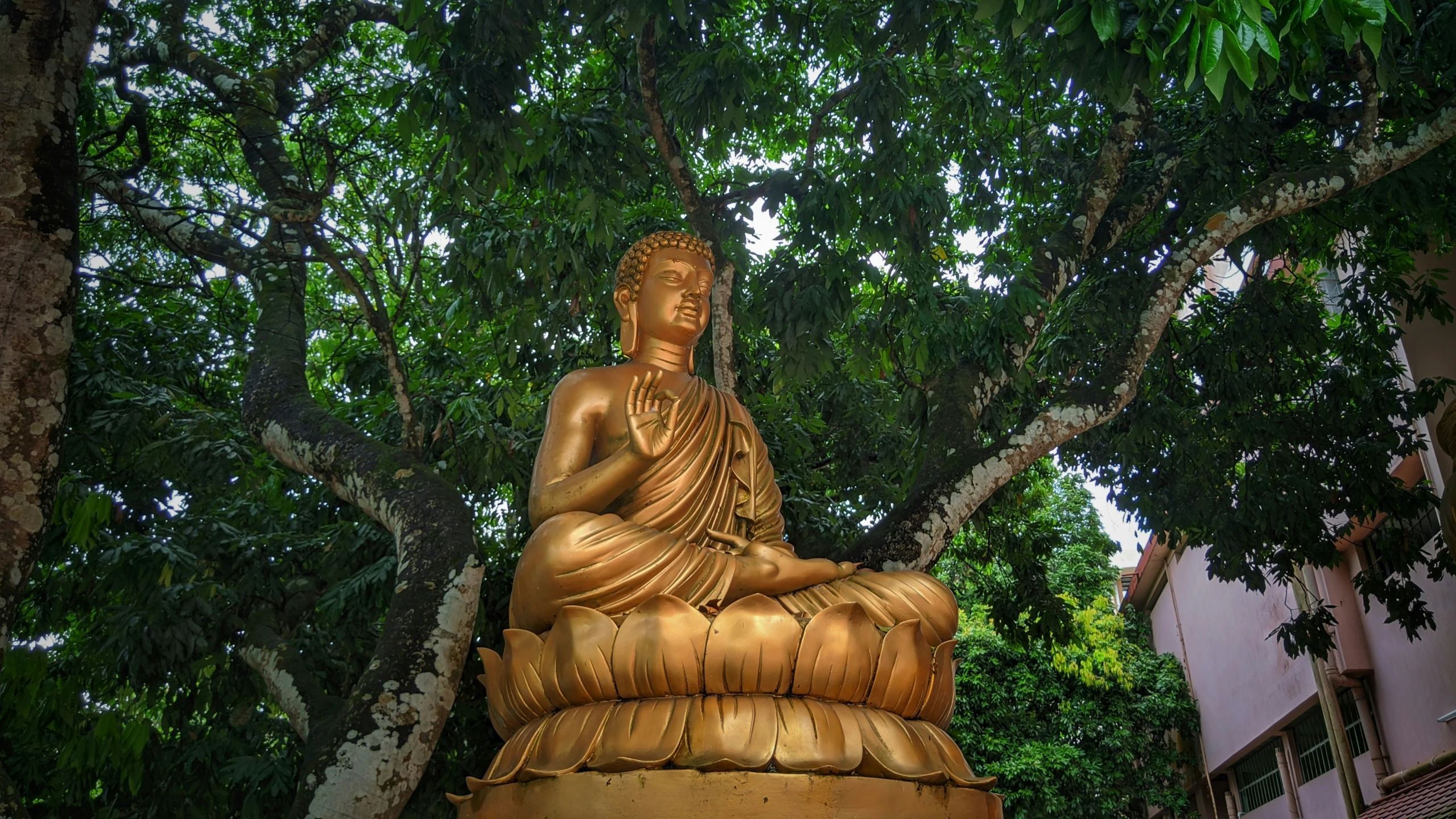 a big gold statue sitting in a lush green park