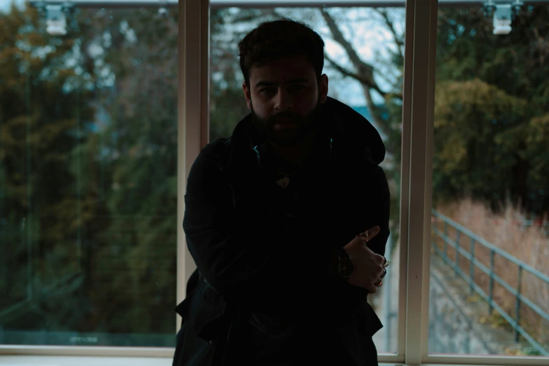 a bearded man is leaning against a window