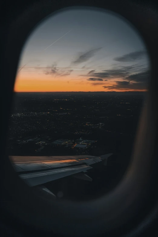 an airplane window is shown showing the sunset