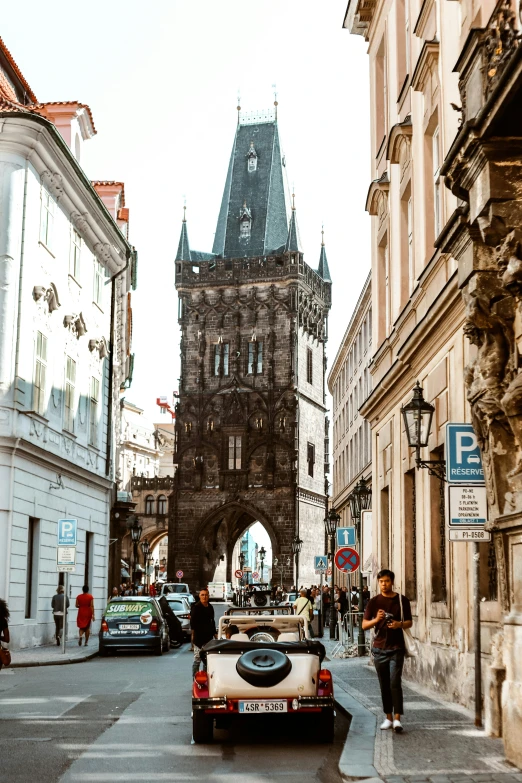 traffic travels down a narrow city street under an ornate clock tower