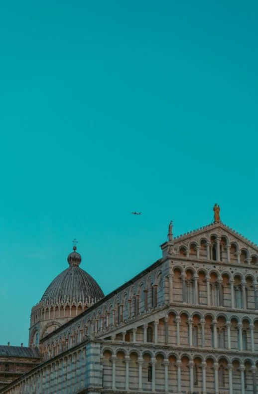 a tall building with a bell tower, two towers and an airplane in the sky