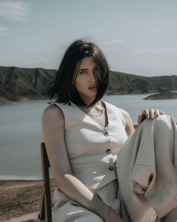 the woman is sitting on the edge of a cliff overlooking the water