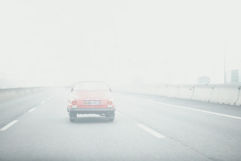 a red car going down the highway in the rain