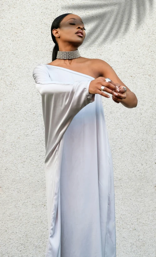 a woman in a white dress holding onto a silver celet