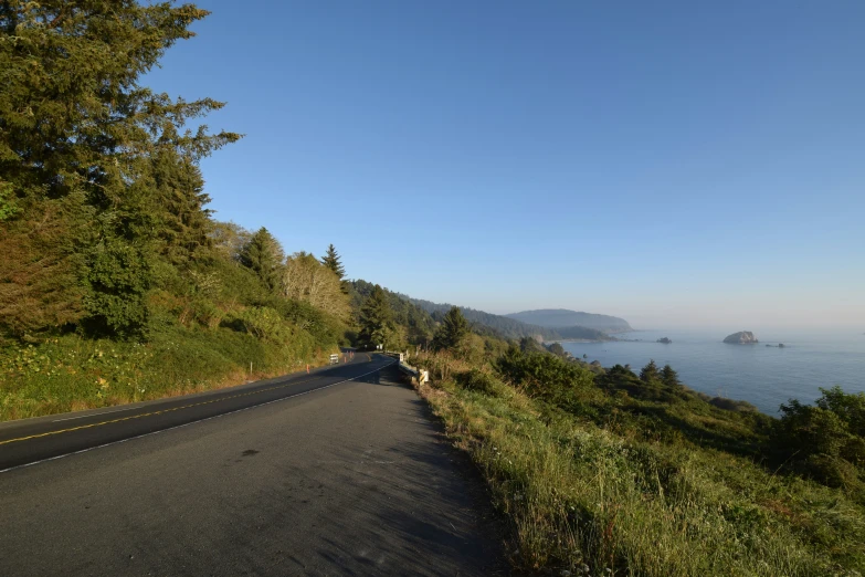 an empty road along a cliff next to the ocean