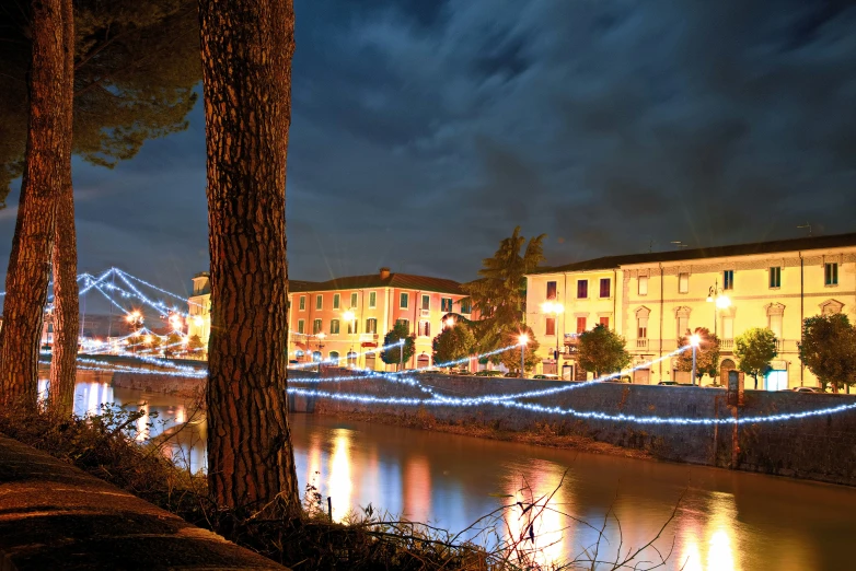 the lights on a building reflect in a canal