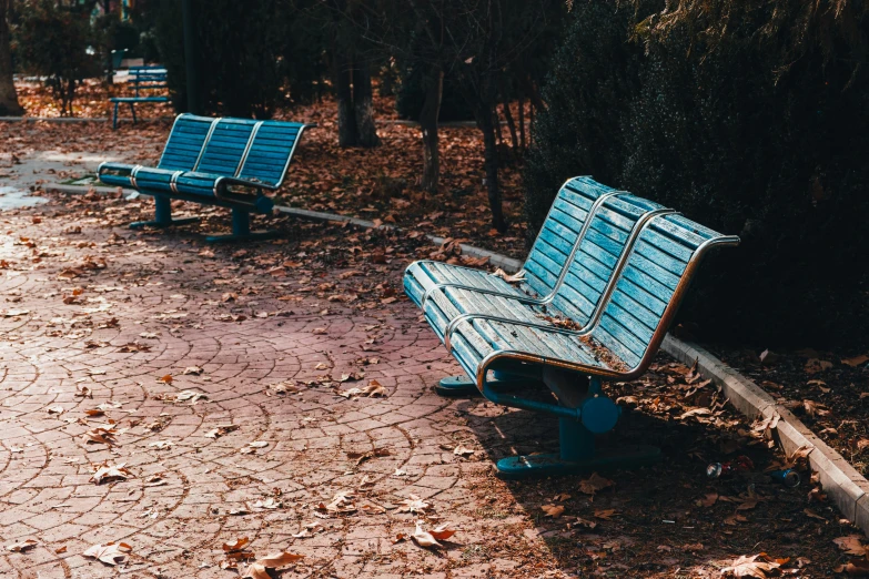 an empty park bench is sitting next to another bench