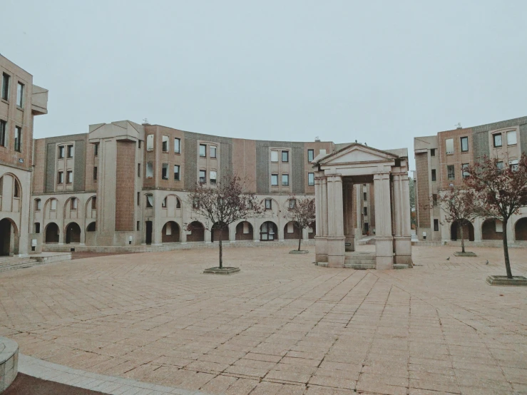 the courtyard of a large building with columns and some trees in front of it