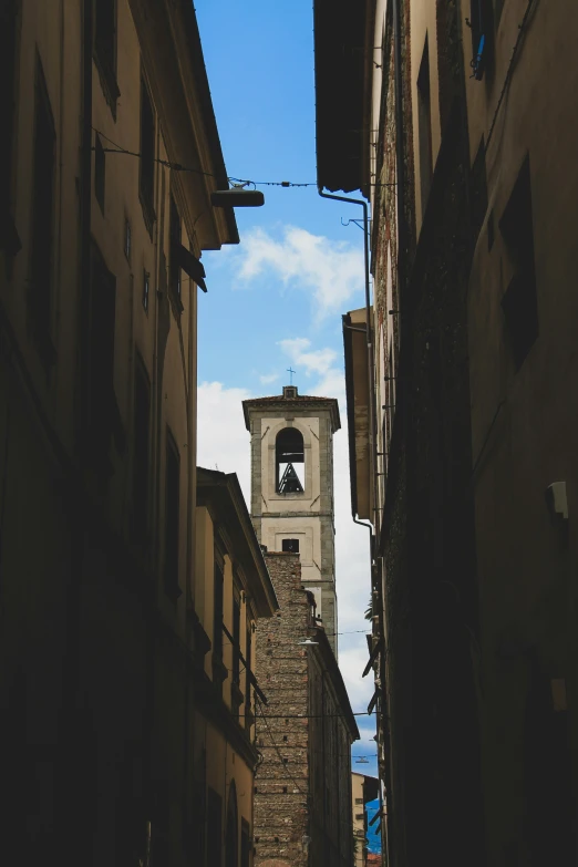 a bell tower rises above an alleyway in a city