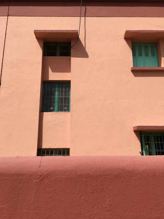 two green windows and a street sign in front of an orange wall