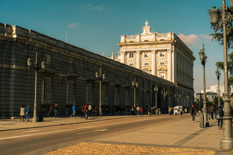 people walking down the sidewalk in front of old buildings