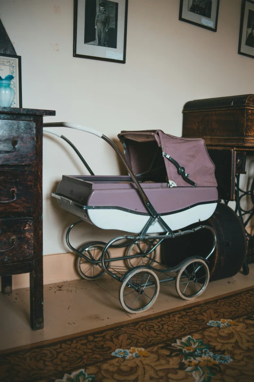 there is a baby's stroller near a dresser and table