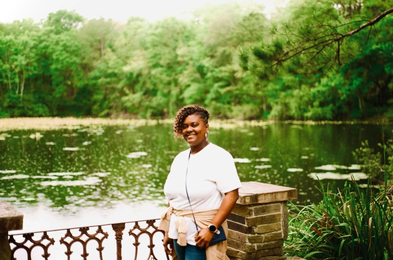 a woman standing on a ledge next to a pond