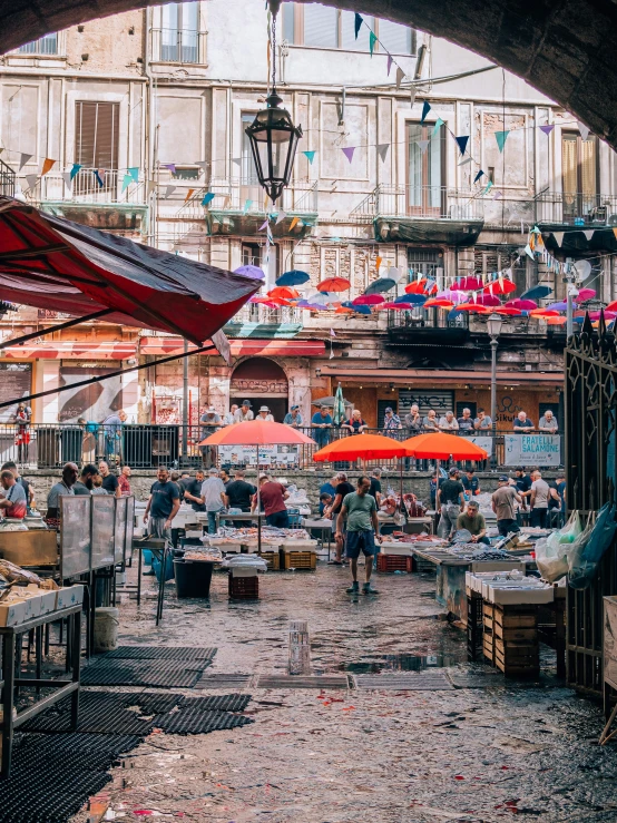 a market with lots of people, umbrellas, and tables